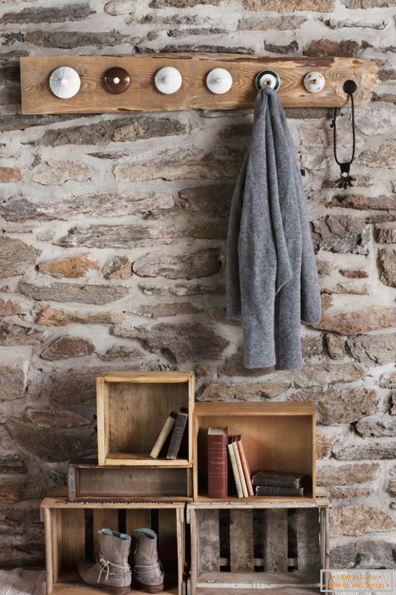 Рустична DIY кулоари во соба со камени ѕидови; палто штипки направени од стариот кина капаци и стари дрвени гајби на подот како складирање