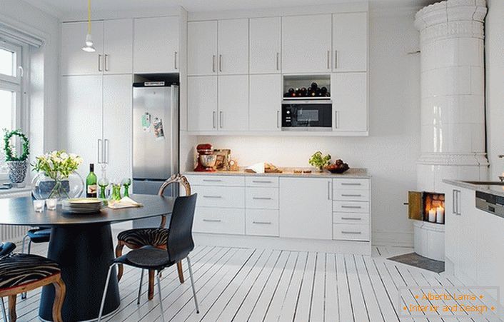 Плочана камина, направена со бели керамички плочки, органски се вклопува во внатрешноста на кујната во скандинавски стил.