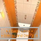 Комбинацијата на бели и портокалови плочки во дизајнот на тоалетот