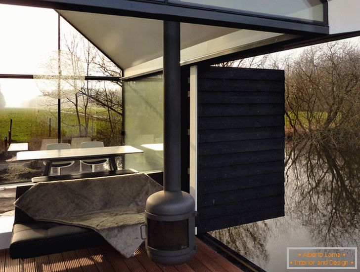 Тераса на мала стаклена куќа покрај езерото во Холандија