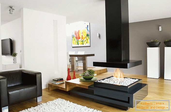 Стилски модерен хај-тек камин го дели просторот за седење и трпезаријата во пространа дневна соба.