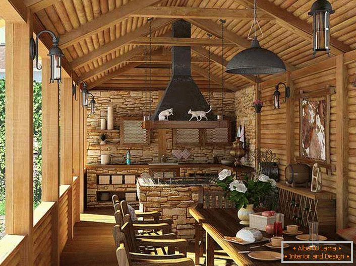 Мала кујна со скара на верандата на селска куќа. Земјата стил е докажано, пред сè, со декорација на ѕидовите и таванот со дрвена рамка.