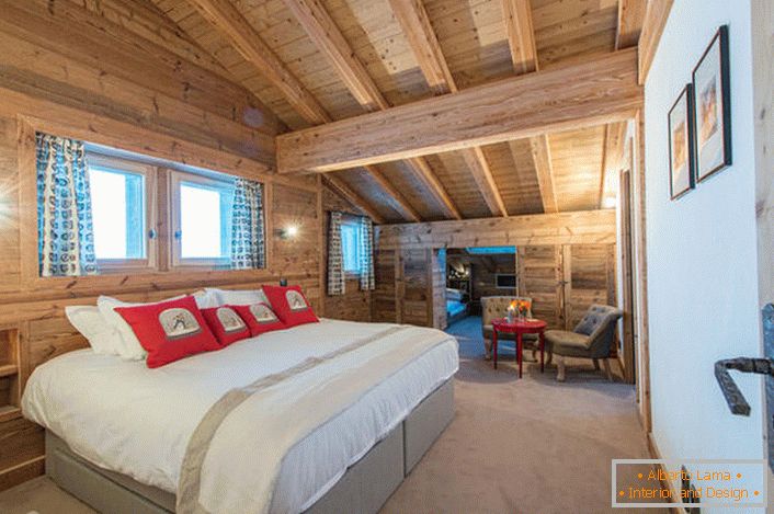 Пространа спална соба на вториот кат на селска куќа од дрвена дрвена куќа. В соответствии со стилем кантри искусственный свет в комнате приглушен. 