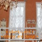 Комбинација на бели завеси и портокалови ѕидови