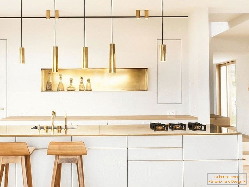 Златна декор елементи во бела кујна со дрвени бар столици