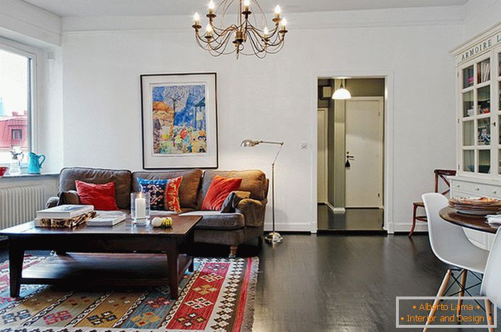 Стилски соба за гости во типичен град стан е украсен со светли перници на троседот и килимот. 