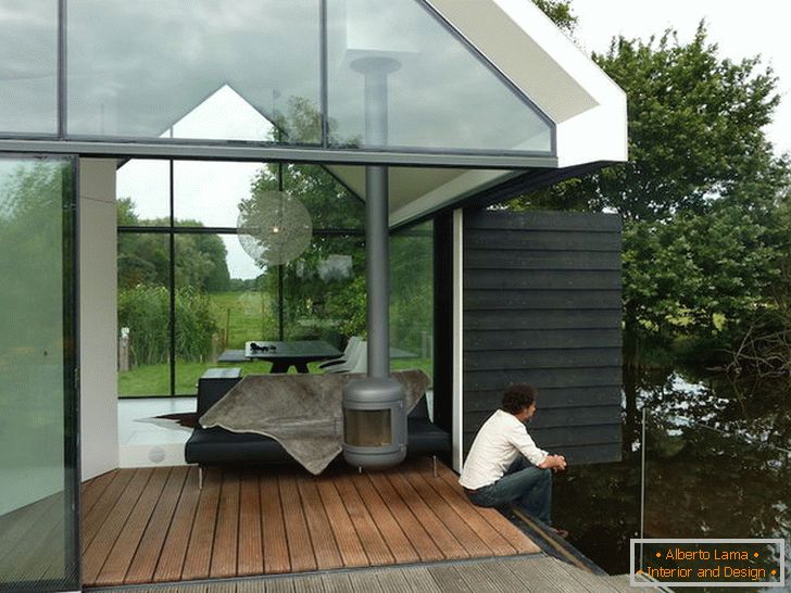Тераса на мала стаклена куќа покрај езерото во Холандија