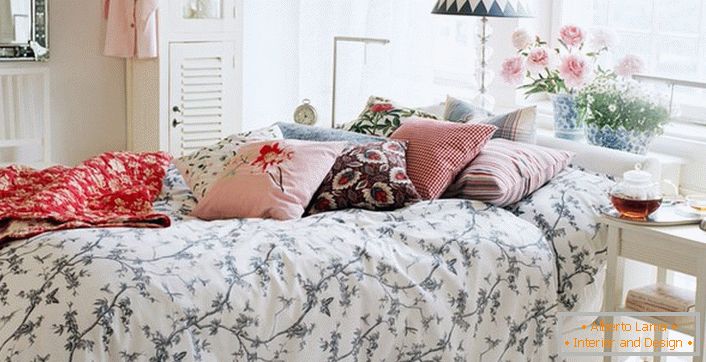 Правилно украсени во стилот на земја кревет. Во најдобрите традиции на земјата на спиење се направени перници од контрастни бои и карирани.