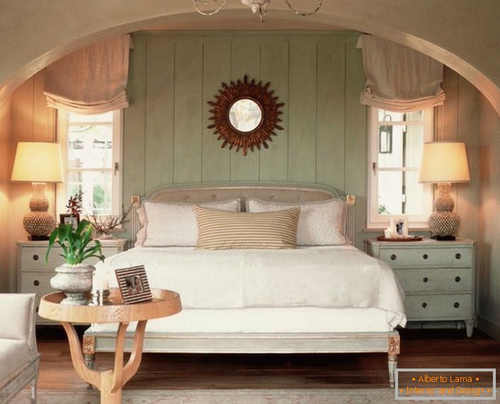 Семејна спална соба во стилот на земјата. Топлината на домот, колку што е можно, е нагласена со мек, волуметриски кревет покриен со перници.