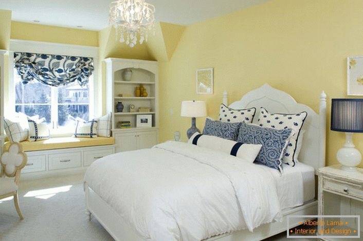 Избледената жолта боја на финишот се усогласува со белите и сините елементи на декор. Невообичаена комбинација е смело решение за спална соба во стилот на земјата.