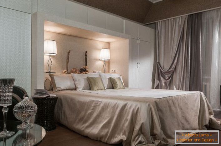 Благородна спална ентериер во стил на уметност-деко. Внимание е привлечено од функционалните кабинети со бела боја. Благодарение на нив, собата станува доста пространа и светла.